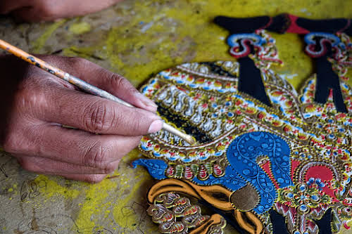 Indonesia. Crafts . Close-up on painting the leather puppet