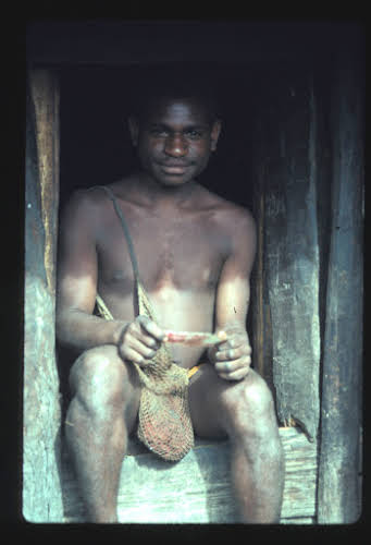 Papua. Tribes Baliem Valley Time Travel. Young Papuan by the Men's Hut